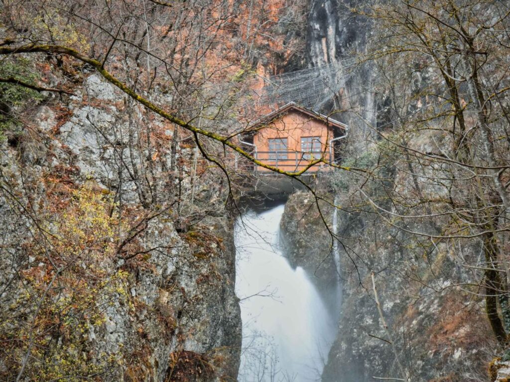 Ulaz u Titovu pećinu okružen gustom šumom i stjenovitim pejzažem.