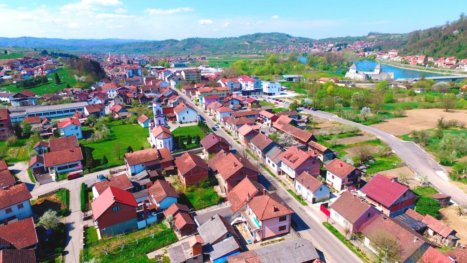 Kostajnica uz rijeku Unu s mostom i zelenilom u pozadini.