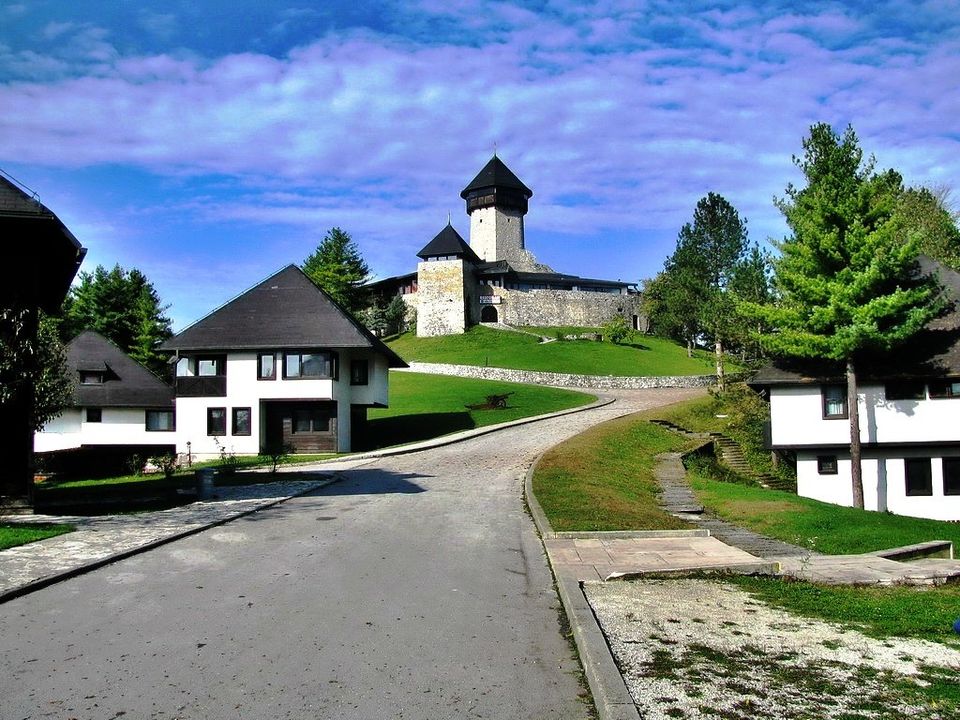 Pogled na Veliku Kladušu s istorijskom tvrđavom i zelenim pejzažima.