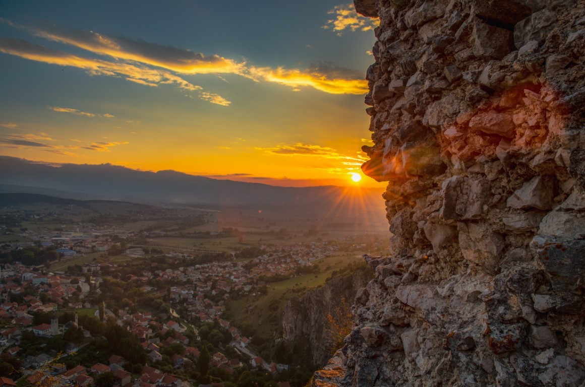 Pogled na Livno s planinama u pozadini i tradicionalnim kamenim kućama.