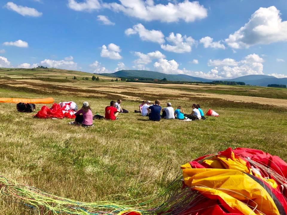 Paraglajder leti iznad planinskog pejzaža Drvara tokom paraglajding takmičenja “Desant na Drvar 2024”, okružena prirodnim ljepotama Bosne i Hercegovine.