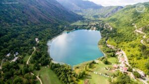 Pogled iz zraka na Boračko jezero, okružen gustom šumom i planinama.