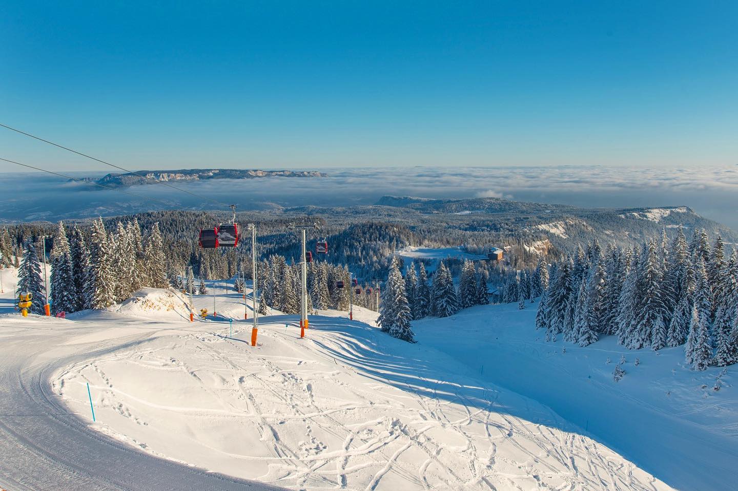 Snijegom prekrivena planina Jahorina s modernim ski stazama i skijašima u pokretu.