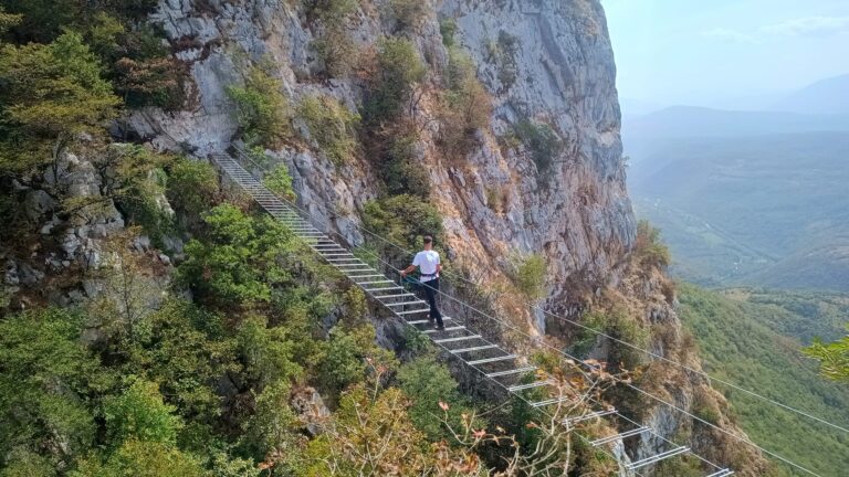 Planinari prelaze viseći most na planini Mulež u Sanskom Mostu, uz pogled na kanjon Sane i sansku kotlinu tokom posjete ferati na Muležu.