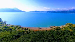 Pogled na Buško jezero okruženo zelenim pejzažima i planinama, pod plavim nebom.