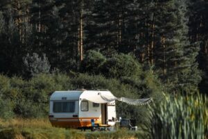 Kamp prikolica uz obalu jezera okružena šumom